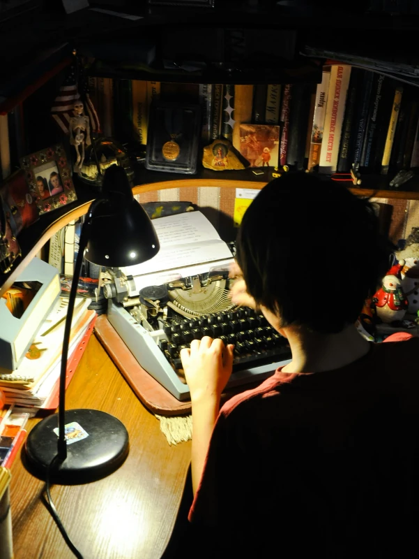 Writer at a typewriter under a desk lamp